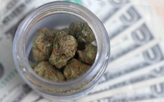 cannabis in jar above cash dollars