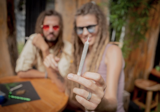 hippy couple holding cannabis joint